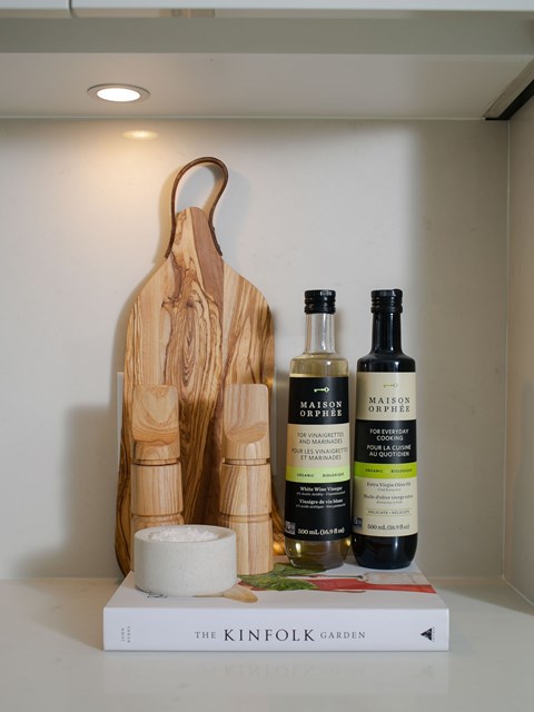 A wooden cutting board and two bottles of Maison du Pain sit on a book titled The Kinfolk Garden.
