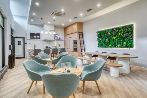 A modern dining area with green chairs and a green plant wall on the wall.