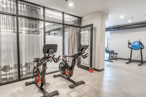 A gym with exercise bikes and a blue exercise ball.