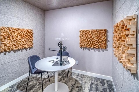 A room with a white table and chairs and two wooden wall art pieces.