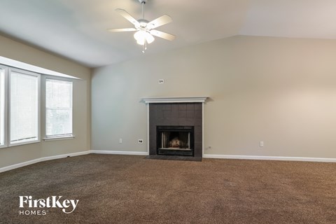 A spacious living room with a fireplace and a ceiling fan.