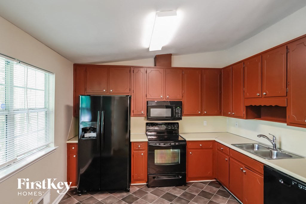 A kitchen with brown cabinets and black appliances.