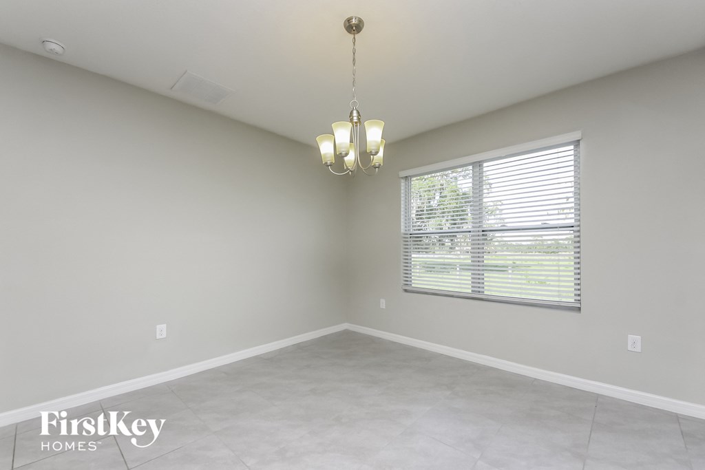 an empty living room with a large window and a chandelier