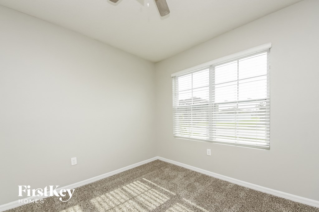 a bedroom with a large window and a carpet