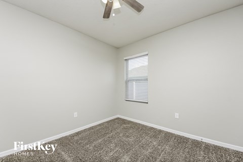 the spacious living room has carpet and a ceiling fan