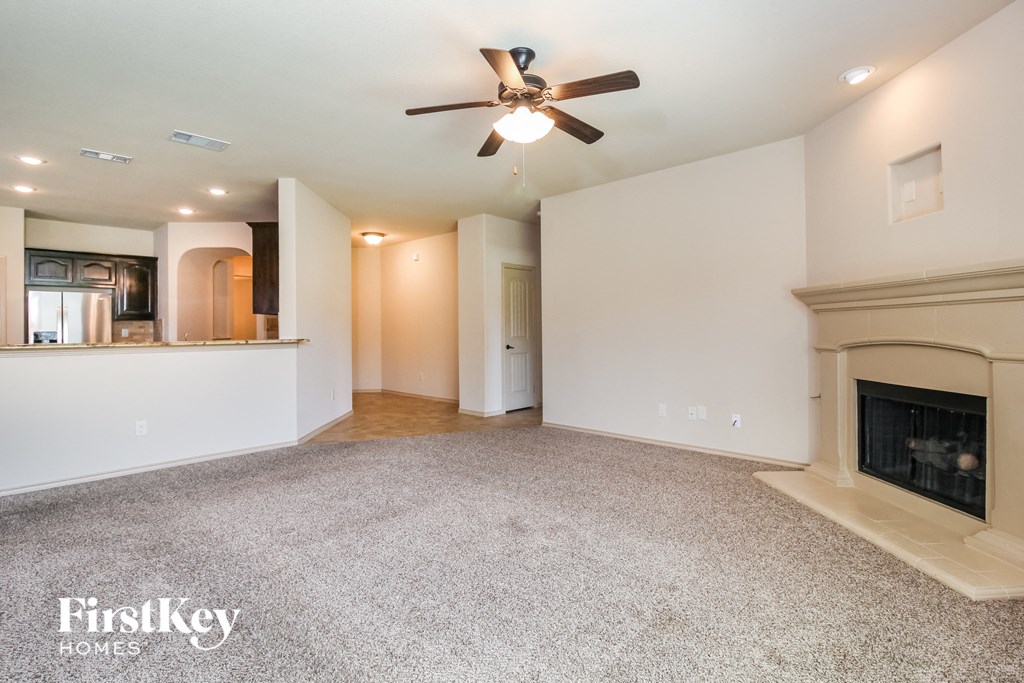 an empty living room with a fireplace and a ceiling fan