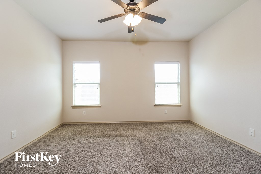 an empty room with a ceiling fan and two windows
