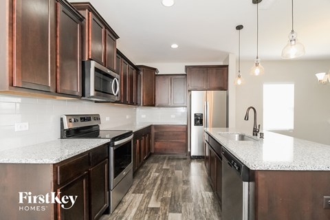 a kitchen with dark wood cabinets and white countertops and a stainless steel refrigerator
