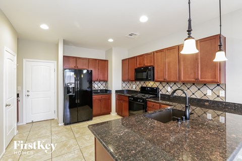 A kitchen with brown cabinets and a granite countertop.