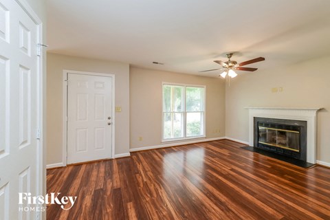 a living room with a fireplace and wooden floors and a ceiling fan