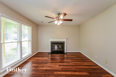 an empty living room with a fireplace and a ceiling fan