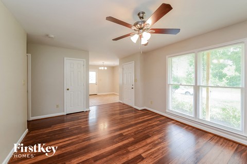 an empty living room with wood floors and a ceiling fan
