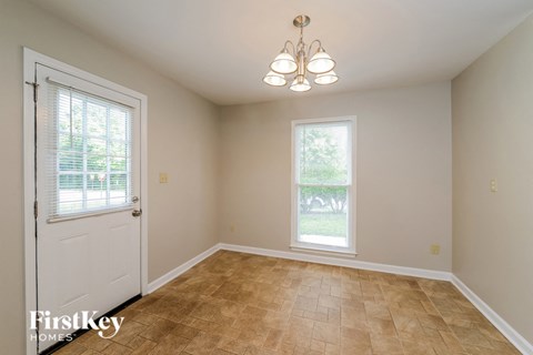 the dining room of a home with a white door and tiled floors