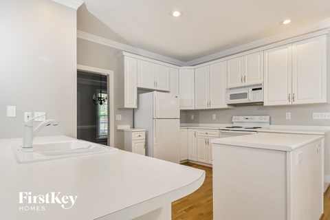 a white kitchen with white counters and white cabinets and a white sink and refrigerator