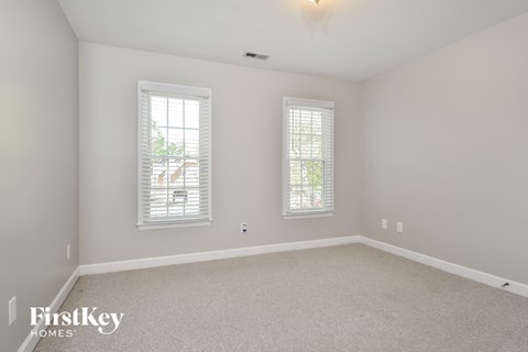 a bedroom with white carpet and two windows