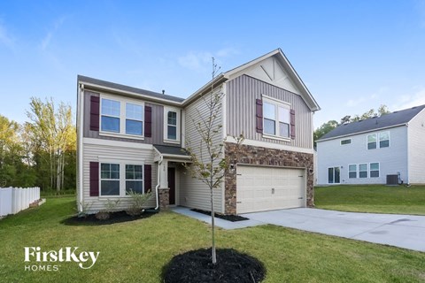 A house with a garage and a tree in front of it.