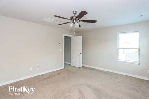 A spacious room with a ceiling fan and a door leading to another room.