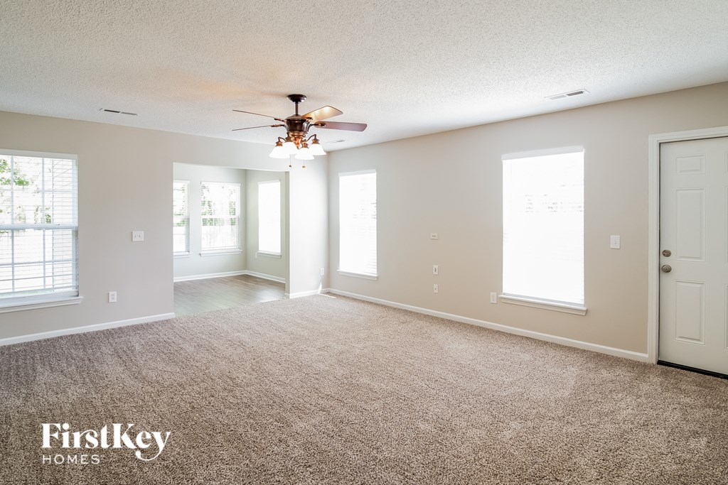 an empty living room with a ceiling fan and a window