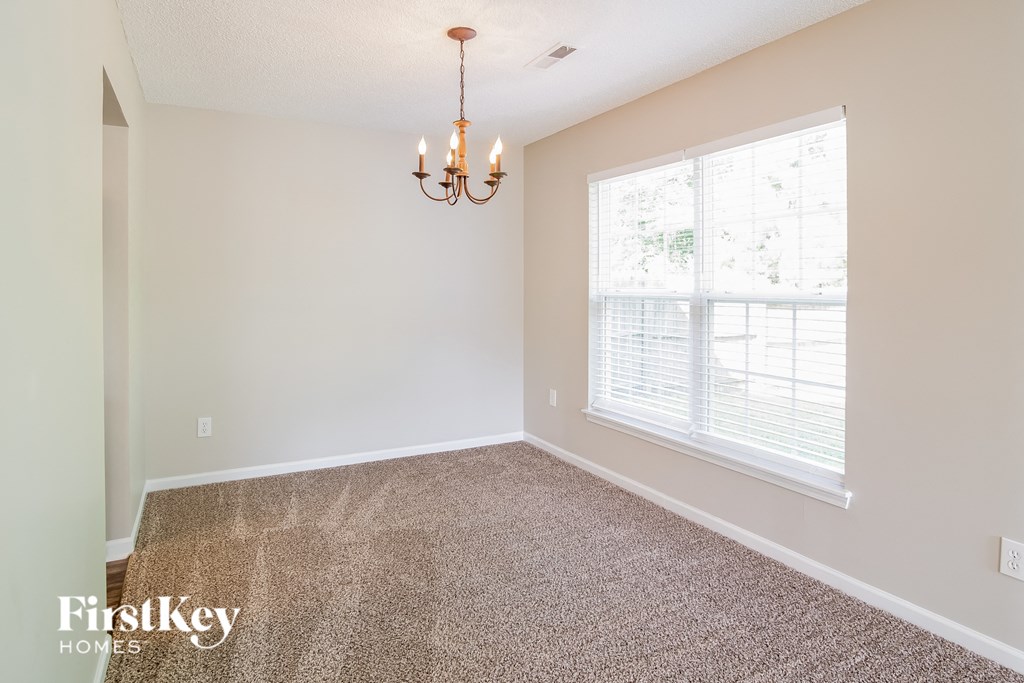 a carpeted living room with a large window and a chandelier