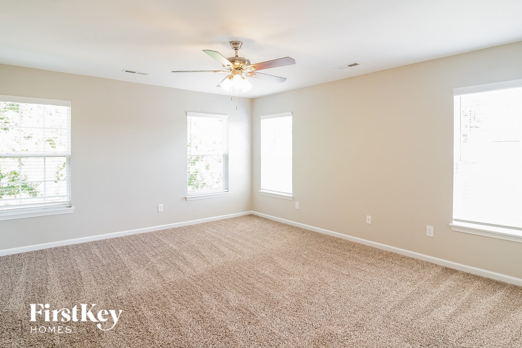 a empty room with a ceiling fan and two windows