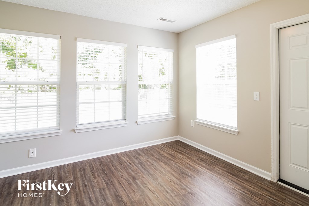 a living room with a hard wood floor and three windows