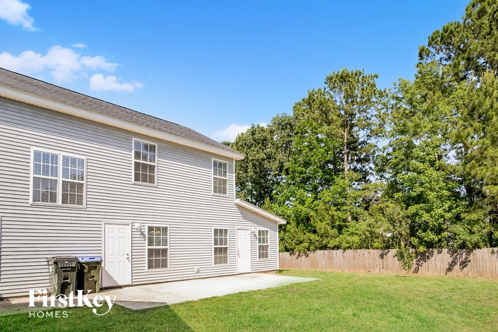 a side view of a white house with a yard and a fence