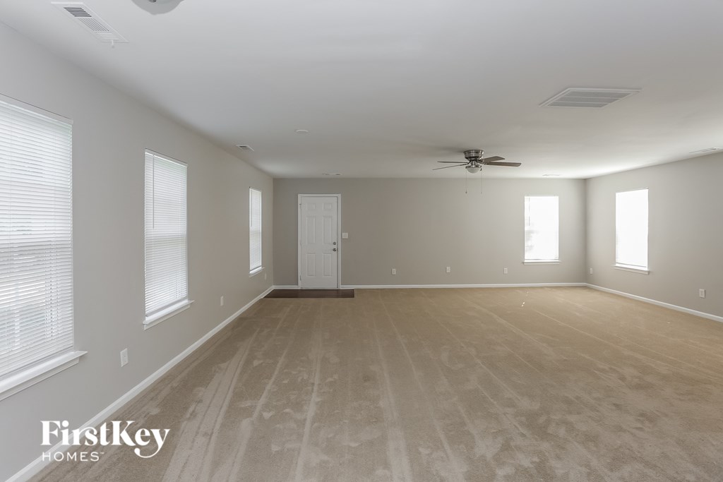 an empty living room with a ceiling fan and windows