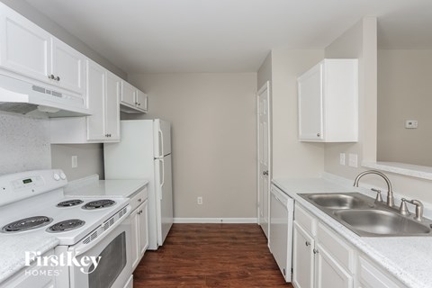 a kitchen with white cabinets and white appliances and a sink