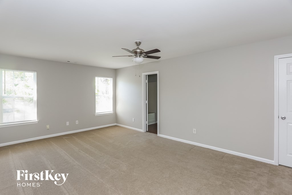 an empty living room with a ceiling fan and a door to a closet