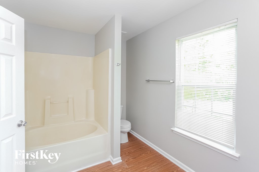 a bathroom with a tub and a window and a toilet