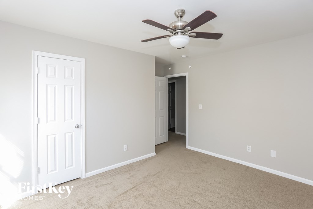 a bedroom with a ceiling fan and a door to a closet