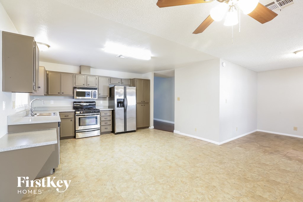 an empty kitchen with stainless steel appliances and a ceiling fan