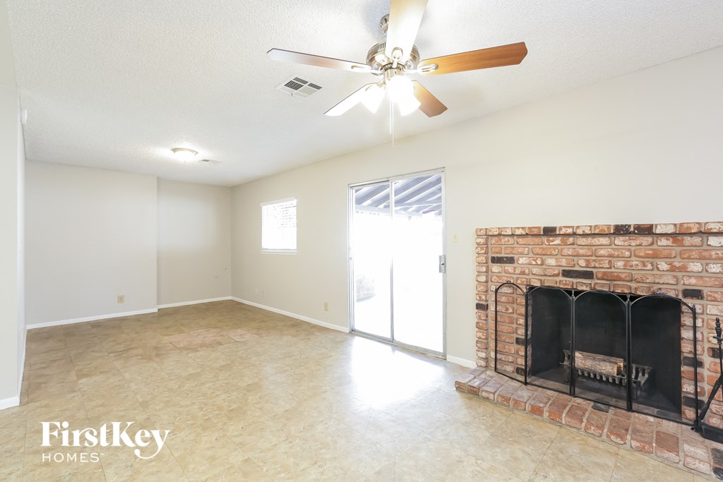 a living room with a brick fireplace and a ceiling fan