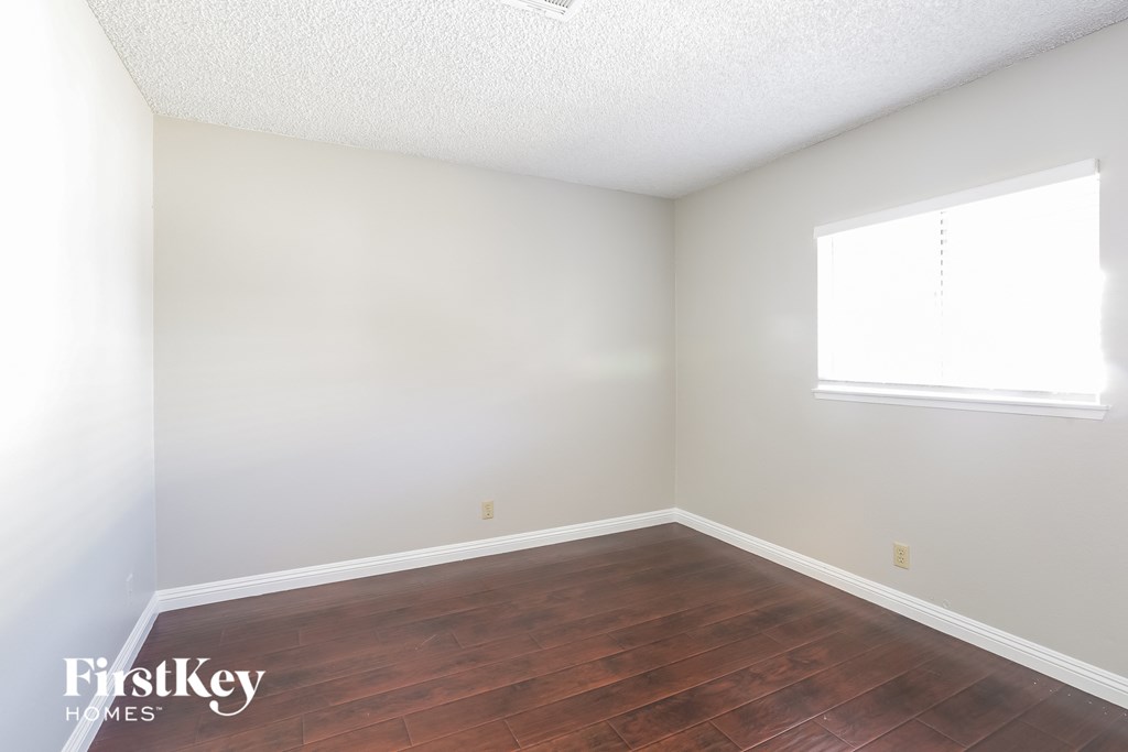 a bedroom with wood floors and white walls and a window