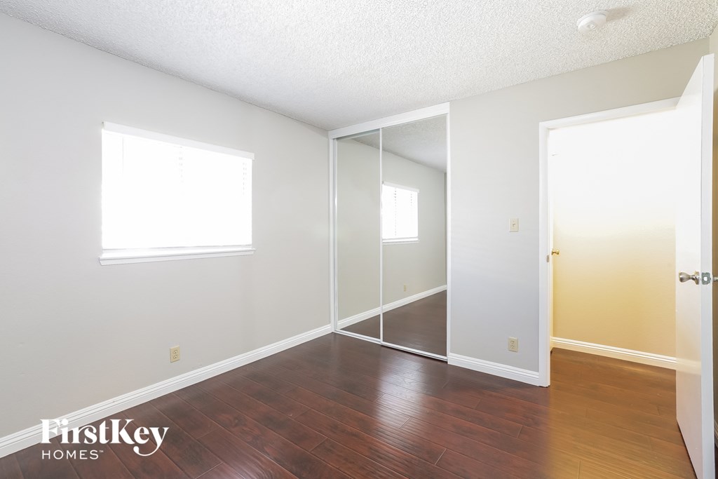 a bedroom with a hard wood floor and a mirrored closet