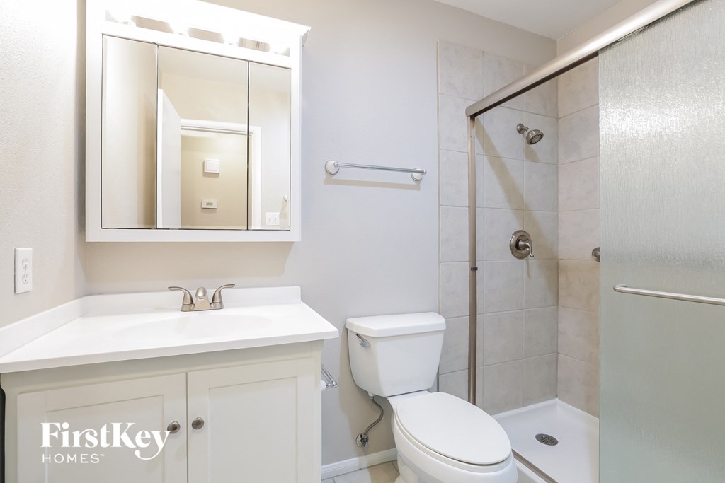 a white bathroom with a shower toilet and sink