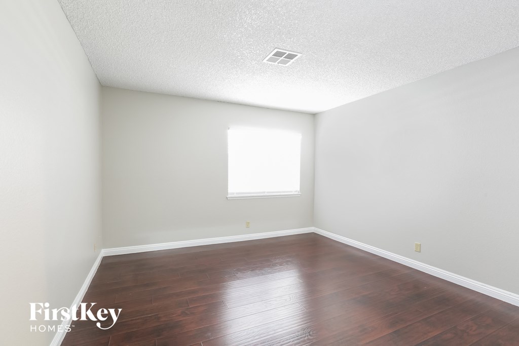 a bedroom with wood floors and white walls and a window