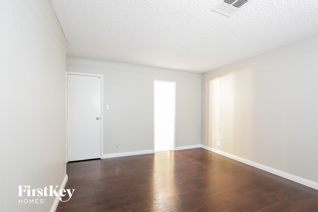 an empty living room with wood floors and white walls