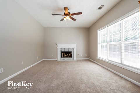 an empty living room with a fireplace and a ceiling fan