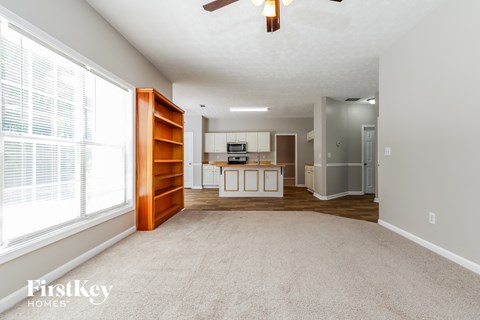 an empty living room with a large window and a kitchen
