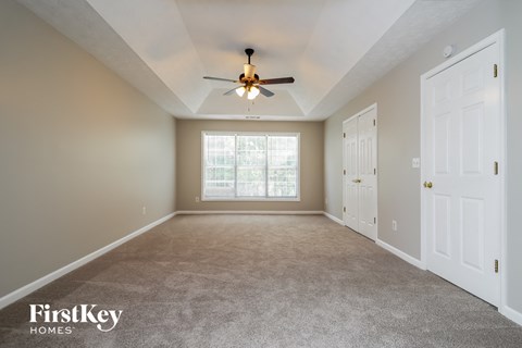 the master bedroom has a ceiling fan and a carpeted floor