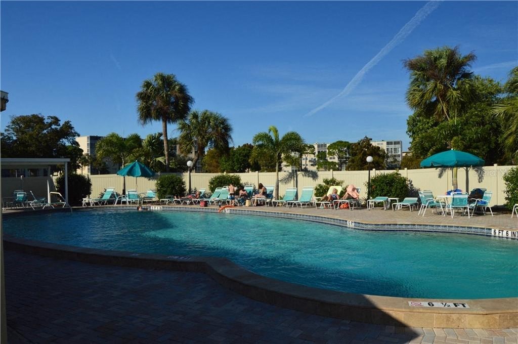 a large pool with chairs and umbrellas and palm trees