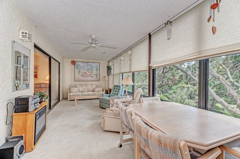 a dining room with a table and a living room with large windows