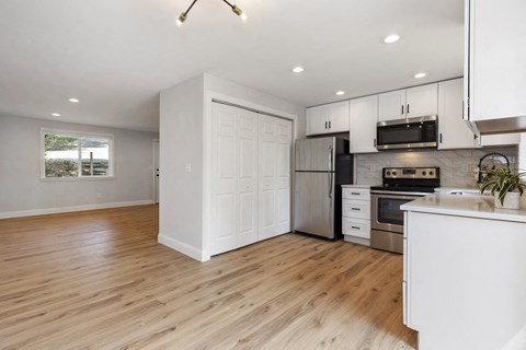 an open kitchen and living room with wood floors and white cabinets