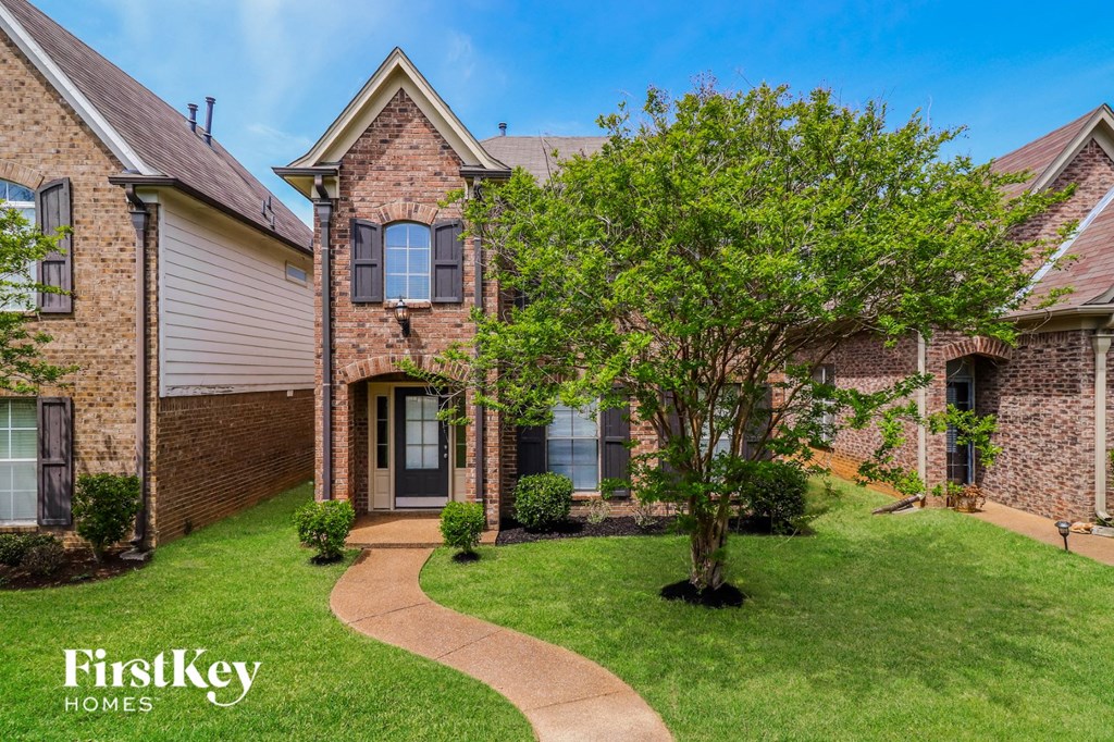 a brick house with a tree in the front yard