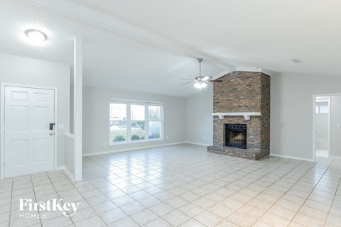 A spacious living room with a fireplace and a ceiling fan.