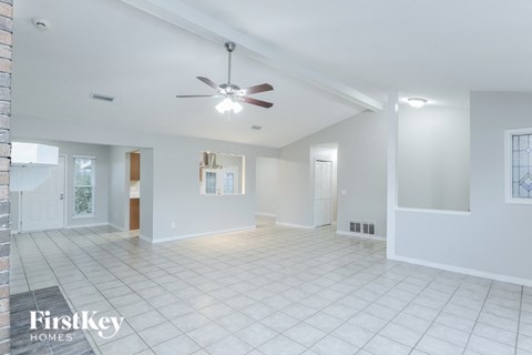 A spacious, empty room with a fan and tiled flooring.