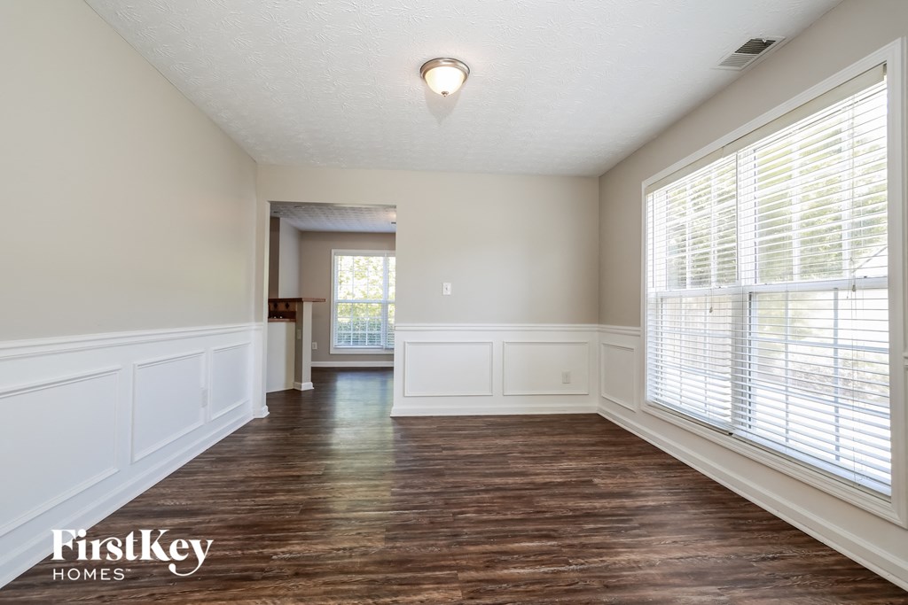 an empty living room with wood floors and large windows