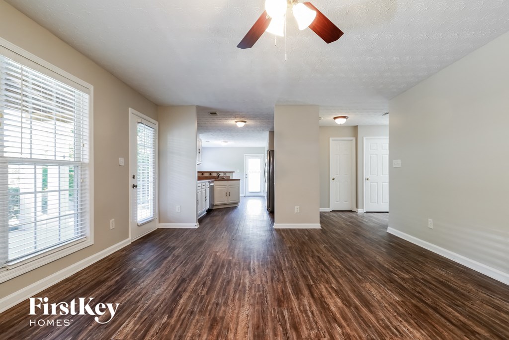 the living room and kitchen of an empty house with a ceiling fan