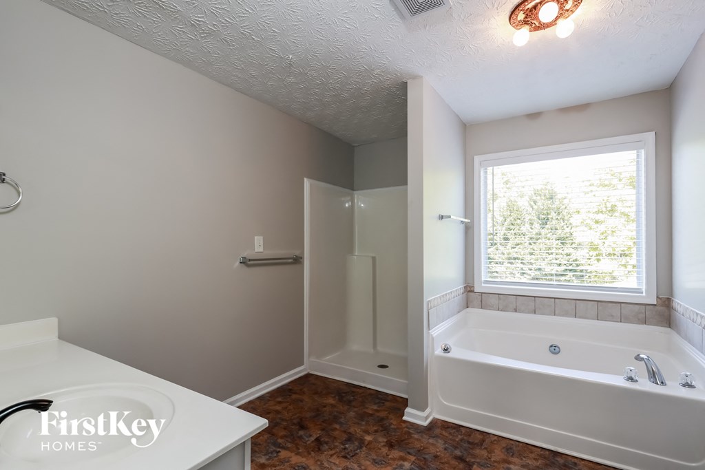 the master bathroom has a large tub and a window